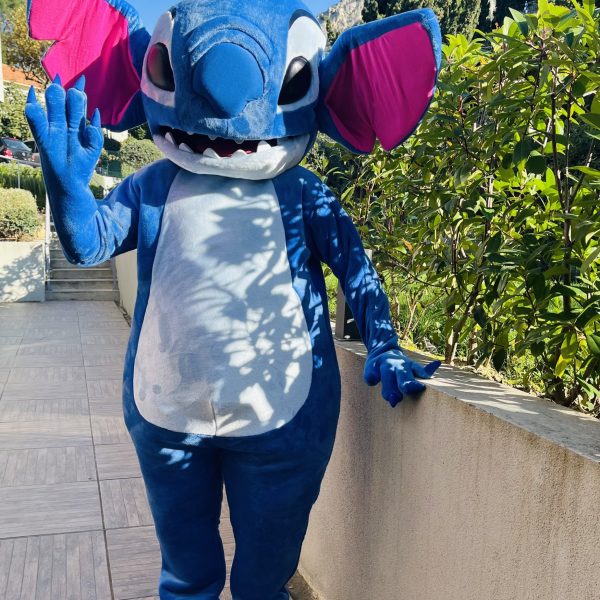 Un costume de mascotte Stitch composé de trois pièces, avec une fourrure bleue douce et moelleuse, représentant le célèbre personnage Disney dans une pose accueillante et joyeuse