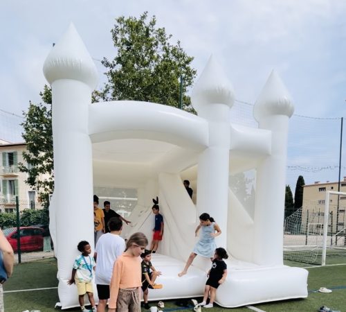 Enfants jouant dans un château gonflable blanc lors de la kermesse à Vence organisée par AS Vence et Kidazur.